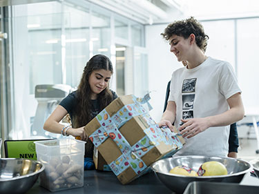 Two students packing a box. Links to Gifts That Pay You Income